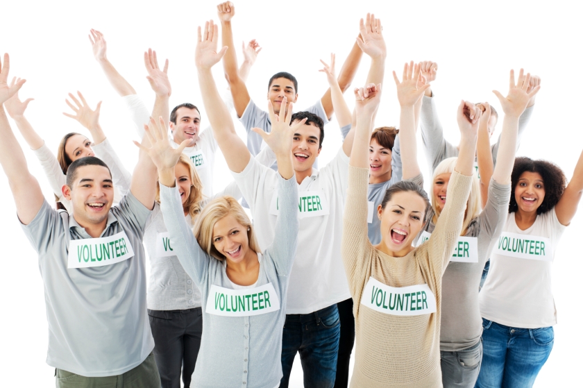 Group of cheerful volunteers with their hands up.